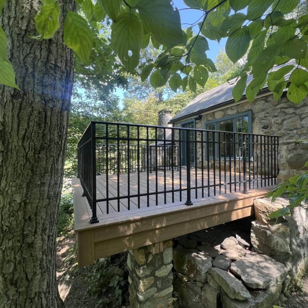 Stone house with a balcony overlooking a rocky stream.