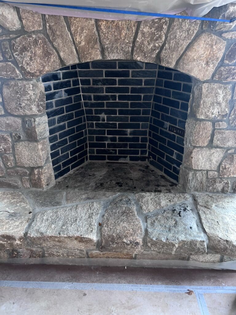 Empty stone fireplace with black interior bricks.