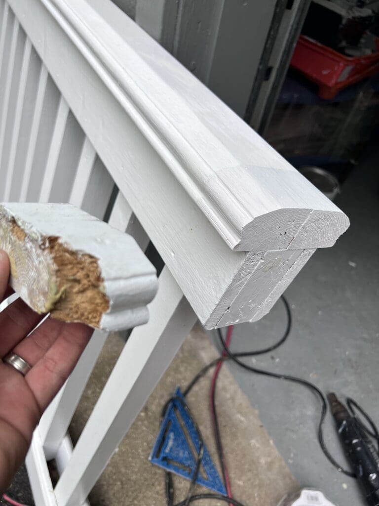 Close-up of a white wooden banister post with a damaged corner.