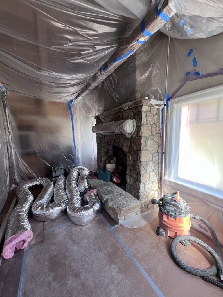 Room under renovation with plastic-covered walls and construction materials.