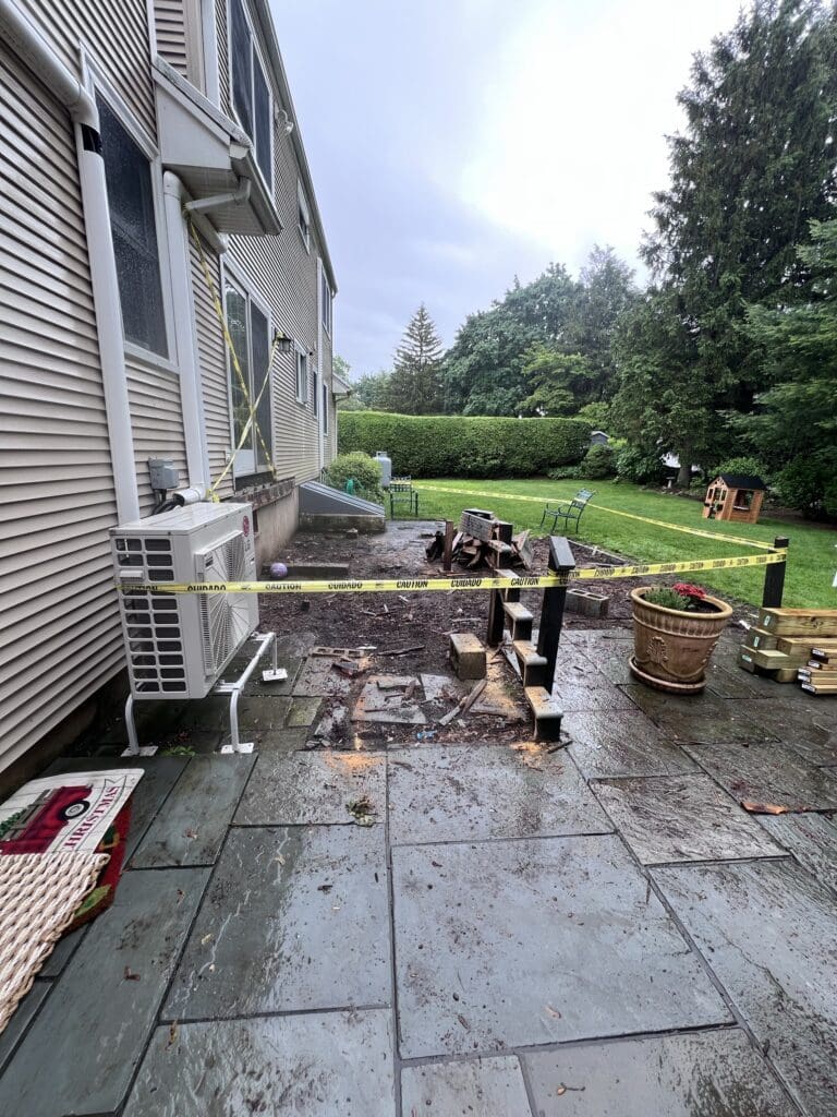 A backyard patio under renovation with construction tools and materials scattered.
