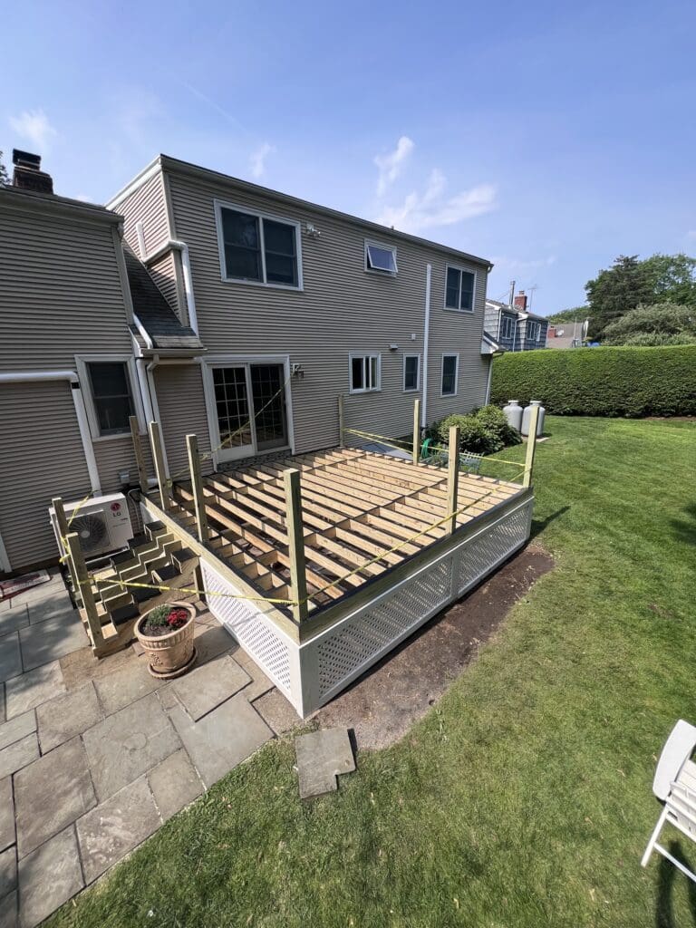 Backyard deck frame under construction beside a house.