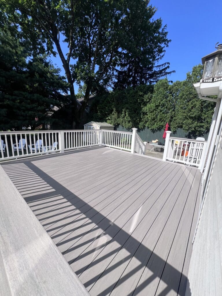 Spacious outdoor deck with light gray flooring and white railings.