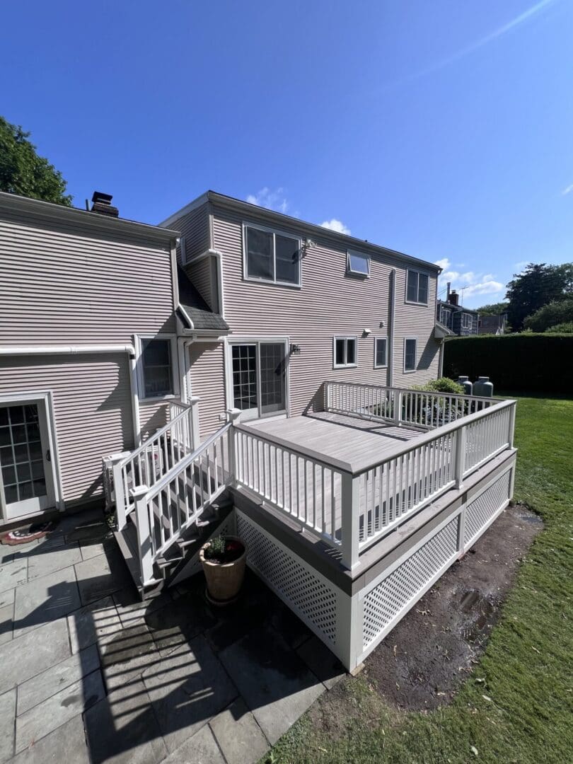 A spacious white wooden deck attached to a two-story house.