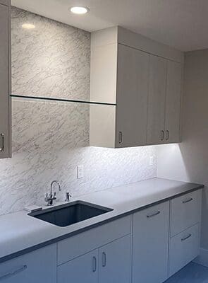 Modern kitchen countertop with marble backsplash and black sink.