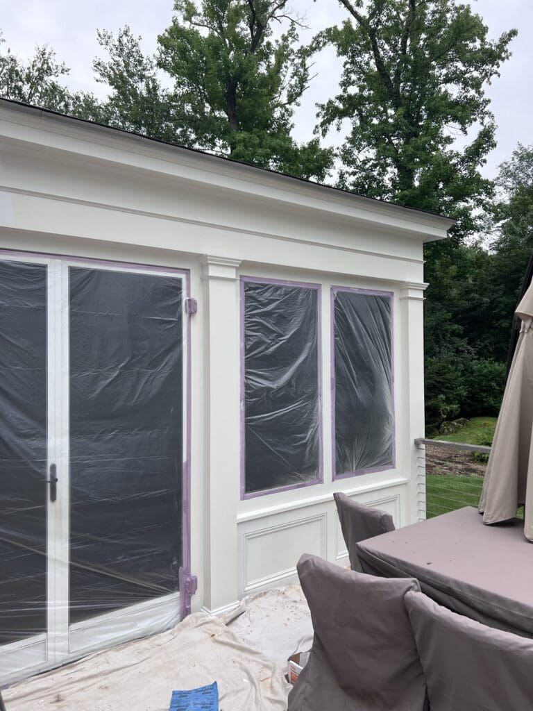 White sunroom with sliding glass doors and outdoor furniture on a patio.