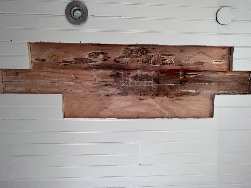 A large, rustic wooden plank mounted on a white wall with two lights above it.