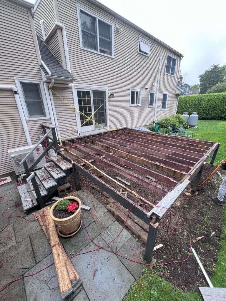 A backyard deck under construction with wooden beams and stairs.