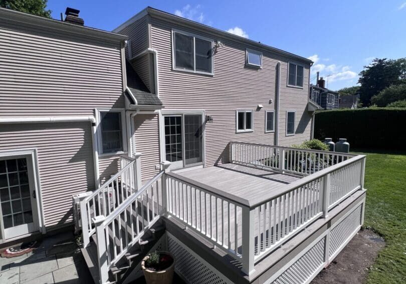 A spacious white wooden deck attached to a two-story house.